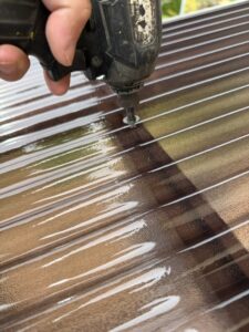 施工中　新しい波板に専用のフックを取り付けるためにインパクトドライバーで穴をあけていきます